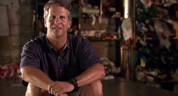 Movie still from “Morning Light” (2008), directed by Mark Monroe – A person sitting on the ground in a room; Medium shot, Low angle