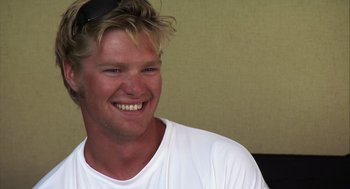 Movie still from “Morning Light” (2008), directed by Mark Monroe – A person wearing a white t - shirt smiling; Close Up shot, High angle