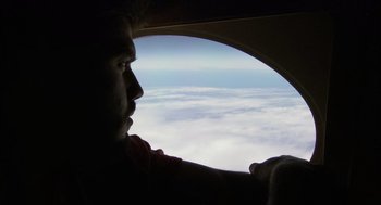 Movie still from “Morning Light” (2008), directed by Mark Monroe – A man looking out a window of an airplane; Close Up shot, Low angle