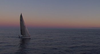 Movie still from “Morning Light” (2008), directed by Mark Monroe – A sailboat sailing on the ocean at sunset; Extreme Wide shot, High angle