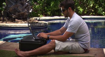Movie still from “Morning Light” (2008), directed by Mark Monroe – A man sitting on the ground using a laptop computer; Wide shot, High angle