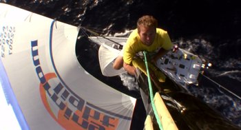 Movie still from “Morning Light” (2008), directed by Mark Monroe – A man riding on the back of a sail boat on a body of water; Extreme Wide shot, Overhead angle