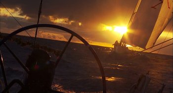 Movie still from “Morning Light” (2008), directed by Mark Monroe – A sailboat in the ocean at sunset with the sun setting; Extreme Wide shot, Low angle