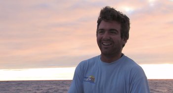 Movie still from “Morning Light” (2008), directed by Mark Monroe – A man smiling for the camera on the ocean; Close Up shot, Low angle