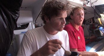 Movie still from “Morning Light” (2008), directed by Mark Monroe – A man holding a spoon while sitting next to another man in a red shirt; Close Up shot, Low angle