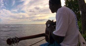 Movie still from “Morning Light” (2008), directed by Mark Monroe – A man sitting on a boat looking out at the ocean; Wide shot, High angle