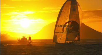 Movie still from “Morning Light” (2008), directed by Mark Monroe – The sun is setting over the ocean with a sail boat; Extreme Wide shot, Low angle