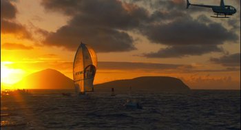 Movie still from “Morning Light” (2008), directed by Mark Monroe – A sailboat in the ocean at sunset with mountains in the background; Extreme Wide shot, Low angle