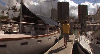 Movie still from “Morning Light” (2008), directed by Mark Monroe – A man standing next to a boat on a dock; Wide shot, High angle