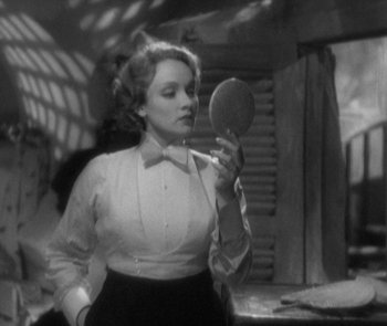 Movie still from “Morocco” (1930), directed by Josef von Sternberg – A black and white photo of a woman looking in a mirror; Medium shot, Over the shoulder angle