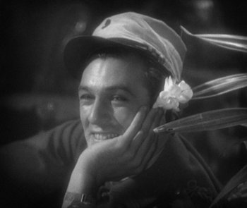 Movie still from “Morocco” (1930), directed by Josef von Sternberg – A young man wearing a baseball cap and smiling for the camera; Close Up shot, Over the shoulder angle