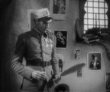 Movie still from “Morocco” (1930), directed by Josef von Sternberg – A man in uniform smoking a cigarette and holding a baseball bat; Medium shot, High angle