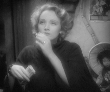 Movie still from “Morocco” (1930), directed by Josef von Sternberg – A black and white photo of a woman holding a cigarette; Close Up shot, High angle