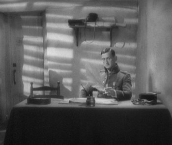 Movie still from “Morocco” (1930), directed by Josef von Sternberg – A man sitting at a table writing on a piece of paper; Medium shot, High angle
