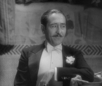 Movie still from “Morocco” (1930), directed by Josef von Sternberg – A man in a tuxedo sitting on a couch; Close Up shot, High angle