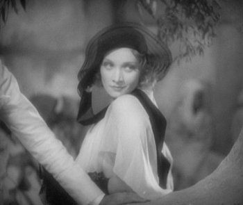 Movie still from “Morocco” (1930), directed by Josef von Sternberg – A black - and - white photo of a woman wearing a hat; Close Up shot, Over the shoulder angle