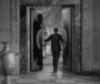 Movie still from “Morocco” (1930), directed by Josef von Sternberg – A black and white photo of a man in a suit walking through a door way; Wide shot, High angle