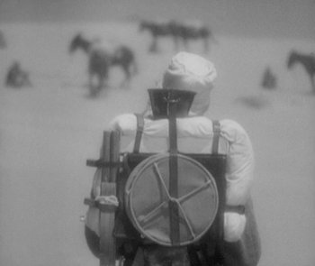 Movie still from “Morocco” (1930), directed by Josef von Sternberg – A person riding a horse drawn carriage in the desert; Wide shot, High angle