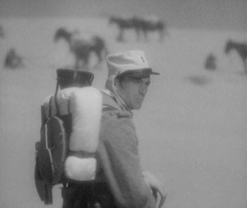 Movie still from “Morocco” (1930), directed by Josef von Sternberg – A man with a large backpack standing in the snow; Medium shot, High angle