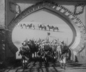 Movie still from “Morocco” (1930), directed by Josef von Sternberg – A black and white photo of a group of men on horses; Extreme Wide shot, High angle