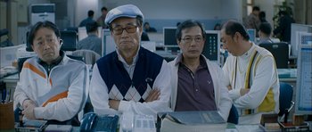 Movie still from “Mother” (2009), directed by Bong Joon Ho – Two men sitting in front of computer monitors; Medium shot, Low angle