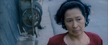 Movie still from “Mother” (2009), directed by Bong Joon Ho – An older woman is standing on the side of the street; Close Up shot, High angle