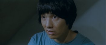 Movie still from “Mother” (2009), directed by Bong Joon Ho – A young man with black hair looking at the camera; Close Up shot, High angle