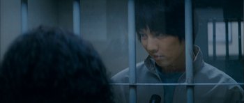 Movie still from “Mother” (2009), directed by Bong Joon Ho – A man is behind bars looking out of a window; Close Up shot, Over the shoulder angle