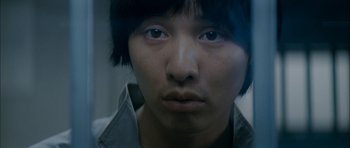 Movie still from “Mother” (2009), directed by Bong Joon Ho – A young man with short black hair looking at the camera; Extreme Close Up shot, High angle