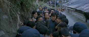 Movie still from “Mother” (2009), directed by Bong Joon Ho – A group of people standing around each other on the street; Wide shot, High angle