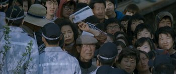Movie still from “Mother” (2009), directed by Bong Joon Ho – A group of people standing around each other in a crowd; Medium shot, High angle