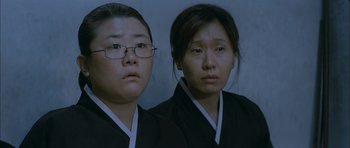 Movie still from “Mother” (2009), directed by Bong Joon Ho – Two asian women wearing black and white clothing; Close Up shot, High angle