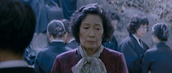 Movie still from “Mother” (2009), directed by Bong Joon Ho – An older woman in a red jacket and a white scarf; Close Up shot, High angle