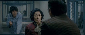 Movie still from “Mother” (2009), directed by Bong Joon Ho – An older asian woman looking at a man in front of a mirror; Close Up shot, Over the shoulder angle