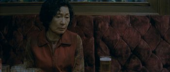 Movie still from “Mother” (2009), directed by Bong Joon Ho – An older woman sitting in a booth with a glass of beer; Close Up shot, High angle