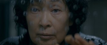 Movie still from “Mother” (2009), directed by Bong Joon Ho – An older asian woman looking out a window; Extreme Close Up shot, Low angle