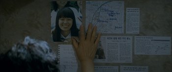 Movie still from “Mother” (2009), directed by Bong Joon Ho – A person's hand on a wall with a map and photos; Extreme Close Up shot, Overhead angle