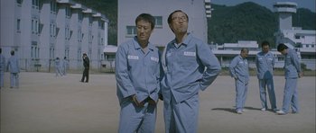 Movie still from “Mother” (2009), directed by Bong Joon Ho – A couple of men standing next to each other on top of a field; Medium shot, Low angle