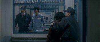 Movie still from “Mother” (2009), directed by Bong Joon Ho – A man standing in front of a mirror in front of another man; Medium shot, Over the shoulder angle