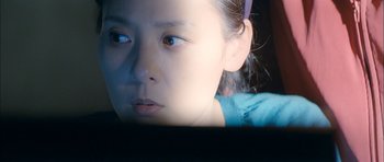 Movie still from “Mother” (2009), directed by Bong Joon Ho – A young girl looking at a computer screen; Close Up shot, Over the shoulder angle