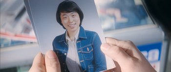 Movie still from “Mother” (2009), directed by Bong Joon Ho – A person holding a picture of a woman in a jean jacket; Extreme Close Up shot, High angle