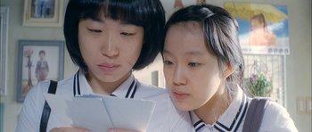 Movie still from “Mother” (2009), directed by Bong Joon Ho – Two young women looking at a piece of paper; Close Up shot, High angle