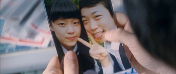 Movie still from “Mother” (2009), directed by Bong Joon Ho – A person holding a picture of a man and a woman; Extreme Close Up shot, Overhead angle