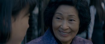Movie still from “Mother” (2009), directed by Bong Joon Ho – An older asian woman smiling for the camera; Close Up shot, Low angle