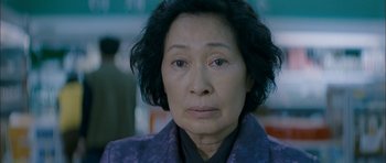 Movie still from “Mother” (2009), directed by Bong Joon Ho – An older asian woman wearing a purple jacket; Close Up shot, Low angle