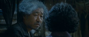 Movie still from “Mother” (2009), directed by Bong Joon Ho – An older man with grey hair looking into the distance; Close Up shot, Over the shoulder angle