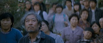 Movie still from “Mother” (2009), directed by Bong Joon Ho – A group of people standing in front of each other; Close Up shot, Low angle