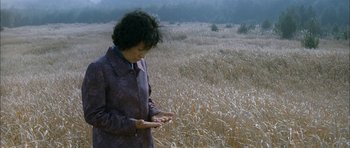 Movie still from “Mother” (2009), directed by Bong Joon Ho – A woman standing in the middle of an open field; Medium shot, High angle