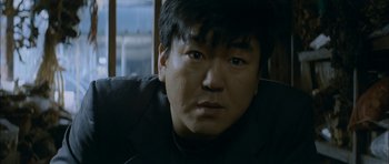 Movie still from “Mother” (2009), directed by Bong Joon Ho – A person wearing a suit; Close Up shot, Low angle