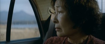 Movie still from “Mother” (2009), directed by Bong Joon Ho – An older woman sitting in the back seat of a car; Close Up shot, Low angle